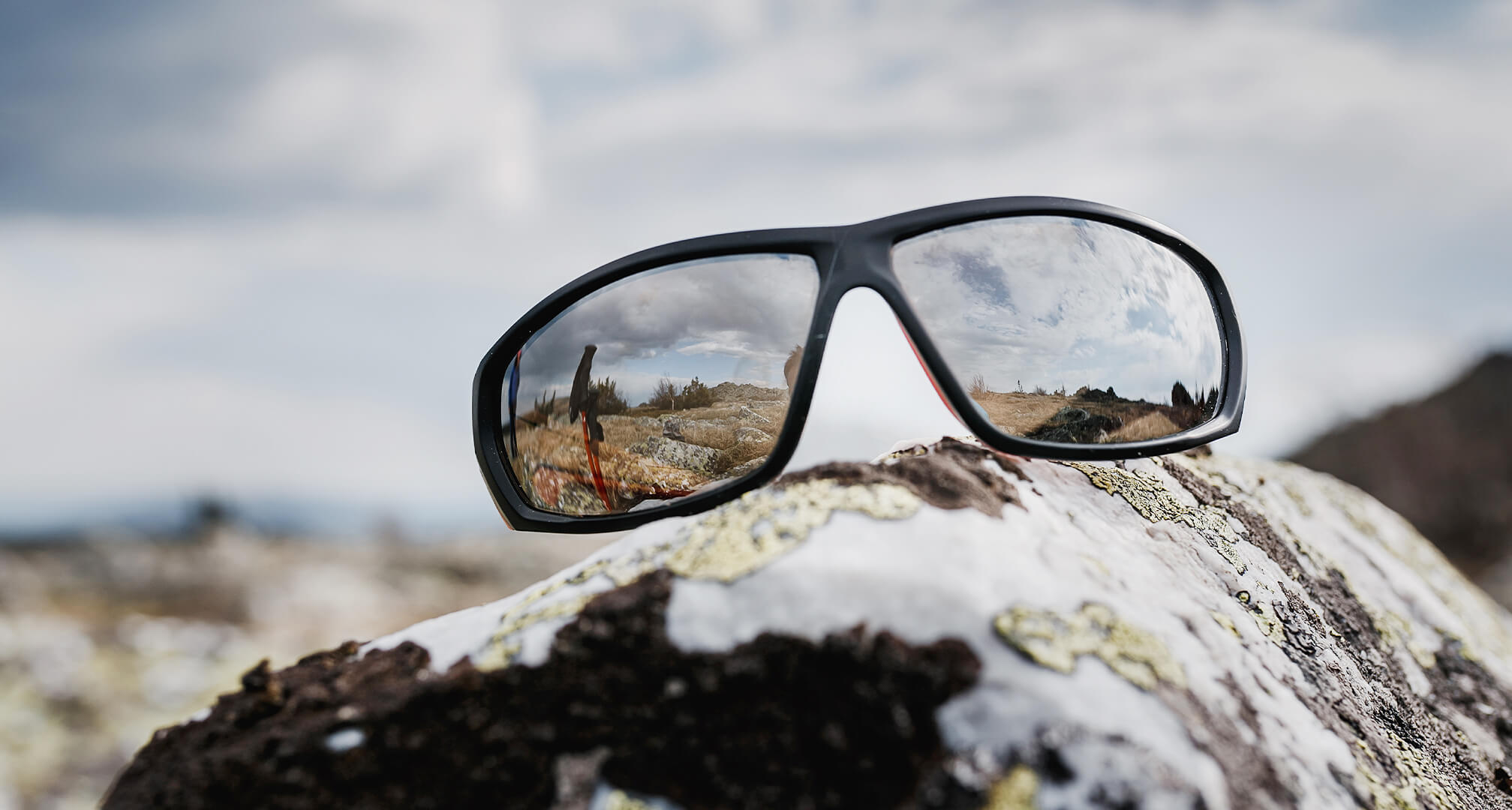 verspiegelte Sonnenbrille auf Felsen sitzend